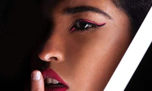 occhio in primo piano di una ragazza con due rige sovrpposte, la prima nera e la seconda fucsia